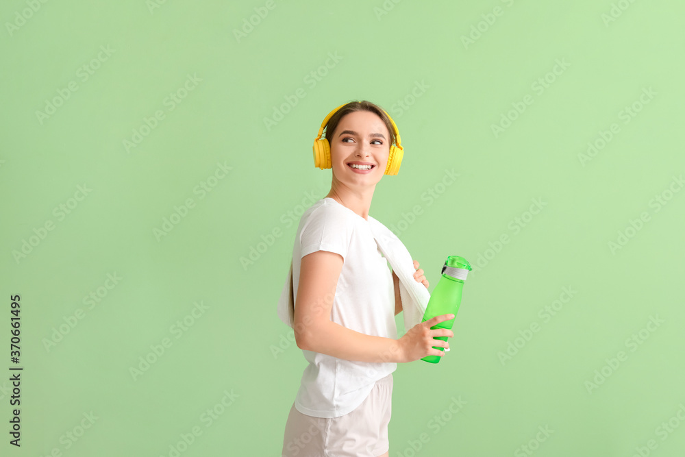 Sporty young woman with headphones and water on color background Sporty young woman with headphones and water on color background