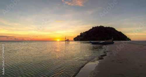 Beautiful sunset view on the ocean with waves and reflection on the sand. A beached foreground log adds interest. Slow motion time lapse 4K footage. Shot at 2160p.