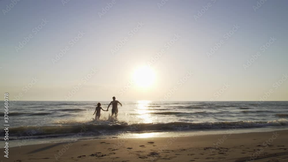 silhouette couple on a beach holding hands and running to the sea silhouette couple on a beach holding hands and running to the sea