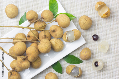 Longan in a white square plate with a cloth background  leave space on the right for the text.