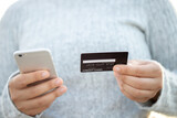 A woman using a credit card to pay for goods online with a mobile phone
