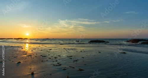 Beautiful sunset view on the ocean with waves and reflection on the sand. A beached foreground log adds interest. Slow motion video 4K footage. Shot at 2160p.