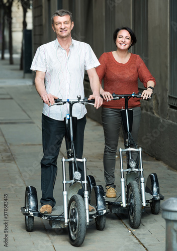 happy american couple with electrkc bikes in vacation on city street. photo