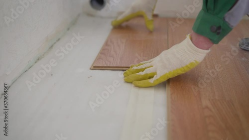 repair, building and home concept - close up of male hands intalling wood flooring. The worker is laying the laminate. photo