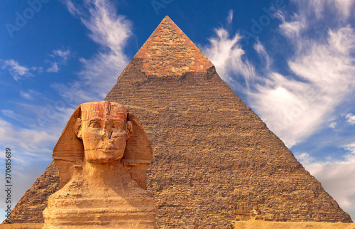 Giant statue of Great Sphinx on the background of the oldest and largest Pyramid of Giza  Pyramid of Cheops   west bank of Nile river  Cairo  Egypt  majestic atmosphere and expressive cirrus clouds