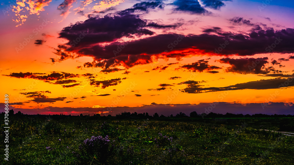 Fototapeta premium Bright sunlight shining through the clouds against the backdrop of a breathtaking evening sky at sunset. panorama, natural composition