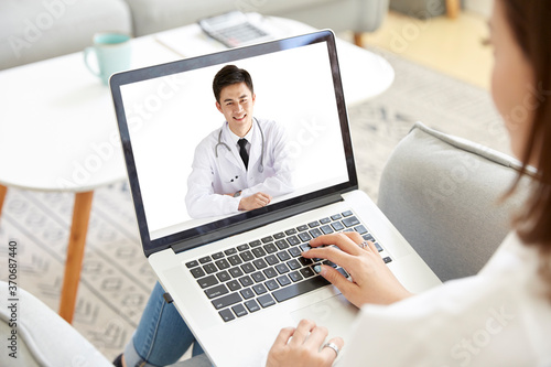 young asian woman talking to doctor via video call using laptop computer photo