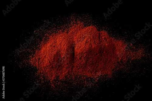 Red paprika, pepper powder pile isolated on black background, top view