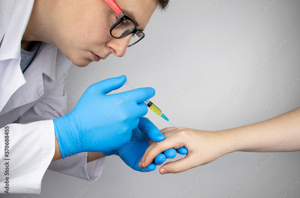 Orthopedic surgeon gives an injection in the finger joint. Treatment of osteoarthritis with hormonal drugs or drugs based on hyaluronic acid. Help with diseases that damage the cartilage of the joint