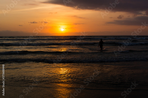 Silhouetted woman in the Indian ocean sunset in Bali, Indonesia 