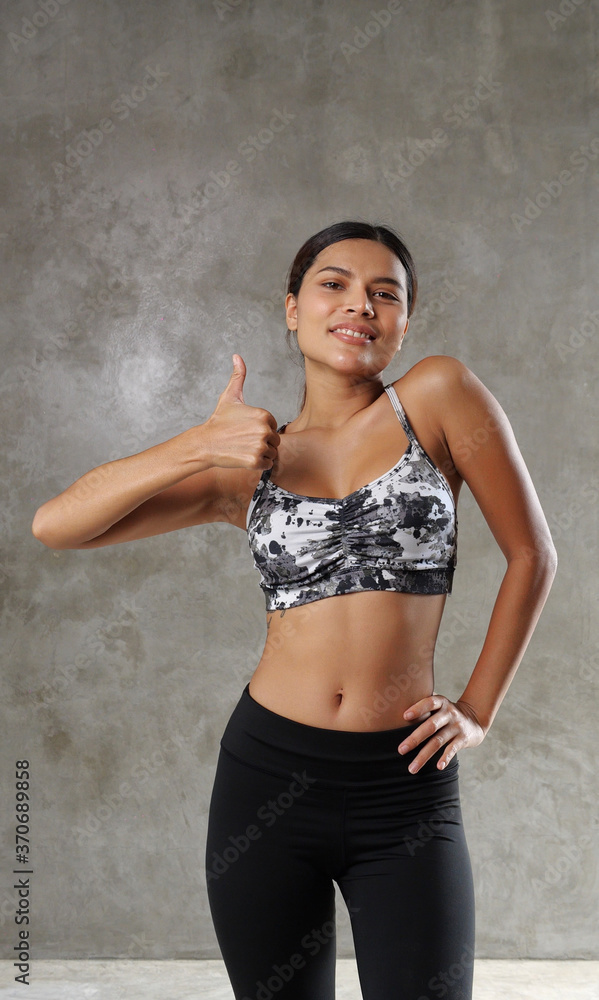 Obraz premium Beautiful young Asian woman at the gym. Happy girl spending her free time at the sport centre