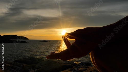 Serenity and yoga practicing, meditation at sunset time, female fingers make zen gesture © Glebstock