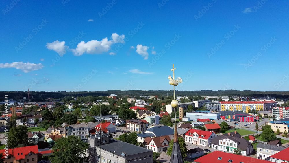 Aerial View of the  Holy Trinity Lutheran Church in Tukums, Latvia. Golden Cock Statue on the Top of Tower. Tukums City Park on the  the Background. Sunny Summer Day.