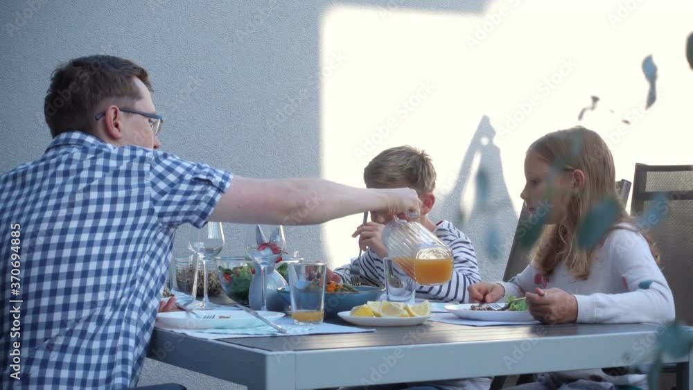 Happy children joyful talking and eating with parents healthy dinner on terrace at garden Happy children joyful talking and eating with parents healthy dinner on terrace at garden