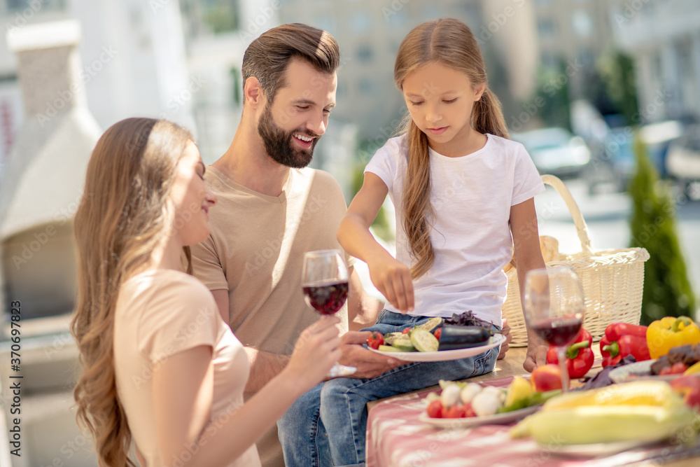 Young cute family having dinner outside and looking cheerful Young cute family having dinner outside and looking cheerful