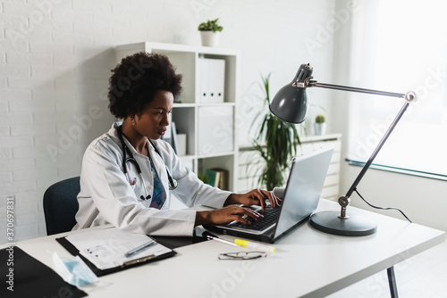 Woman doctor with stethoscope looking at medical papers at her office working hard