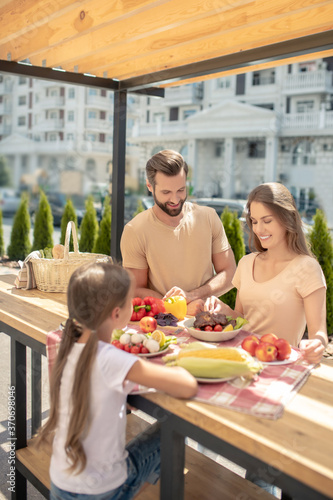 Young cute family having dinner outside and looking pleased © zinkevych