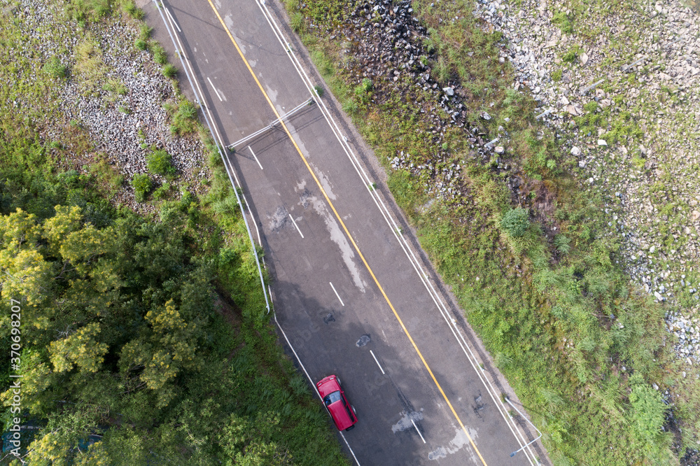Aerial view top down photo from flying drone of asphalt road with red suv car and road around the dam.