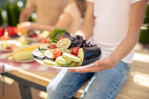 Close up picture of girls hands holding a plate with vegetables