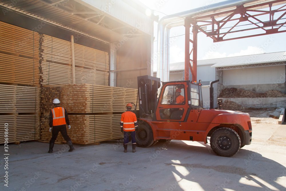 workers load boards with an industrial loader at a sawmill workers load boards with an industrial loader at a sawmill