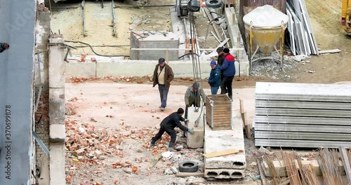 Workers place a reinforced concrete block on the ground during transportation by crane photo