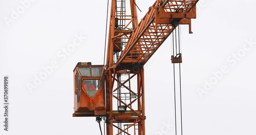 The crane boom rotates to transport cargo at the construction site photo