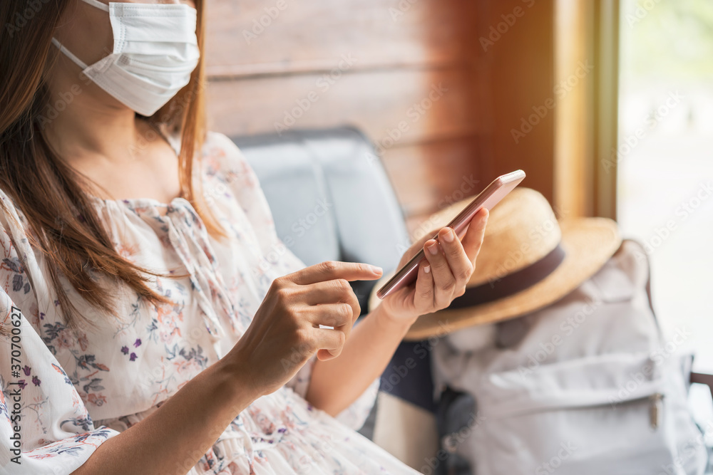 Obraz premium Young asian woman wearing sergical mask using smart phone in cafe while traveling