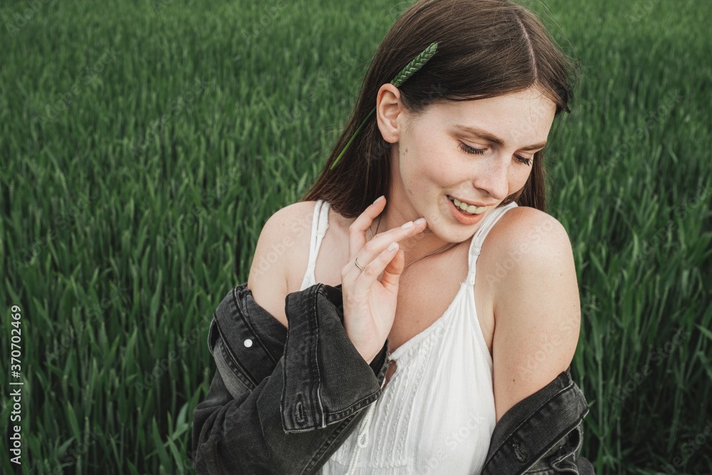 Young Stylish Girl in White Dress and Denim Jacket Spends Time in the Green Wheat Field Young Stylish Girl in White Dress and Denim Jacket Spends Time in the Green Wheat Field