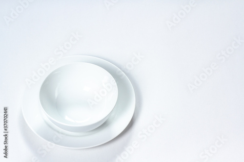 A clean white plate and soup cup stacked on a white background, isolated, there is copy space for text.