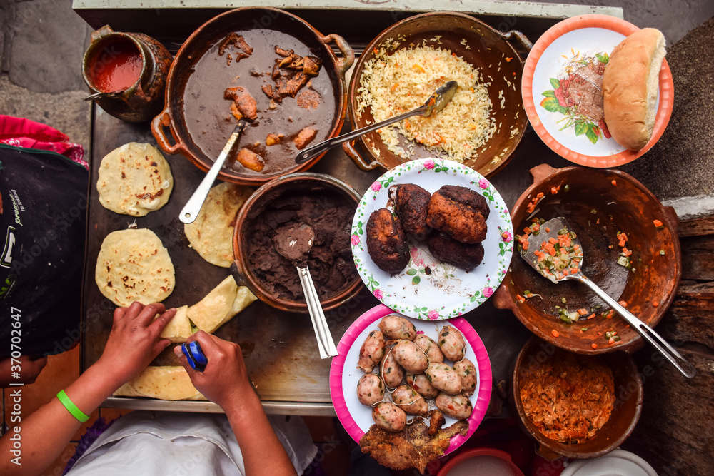 Unrecognizable woman hands cooking over counter full of traditional Guatemalan foods