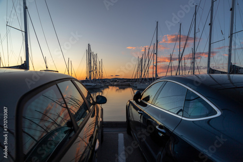 Luxury cars and yachts in a port at sunset
