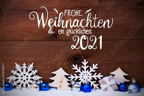 German Calligraphy Frohe Weihnachten Und Ein Glueckliches 2021 Means Merry Christmas And Happy 2021. Blue Christmas Decoration Like Tree, Gift And Ball. Wooden Background With Snow