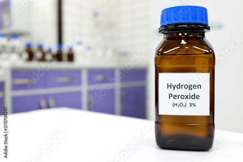 Selective focus of hydrogen peroxide solution in brown amber bottle. Blur laboratory background with copy space. photo