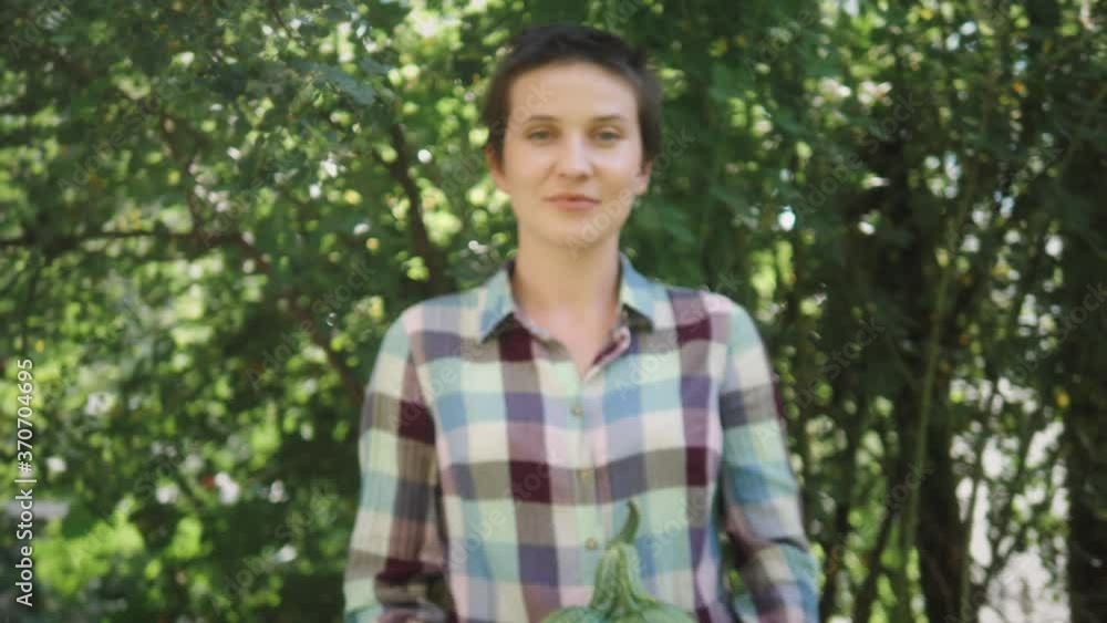 Female agriculturist farmer holding vegetable marrow in hands. Farmer show agricultural product to camera. Concept of harvesting agricultural product to the consumer. Female agriculturist farmer holding vegetable marrow in hands. Farmer show agricultural product to camera. Concept of harvesting agricultural product to the consumer.