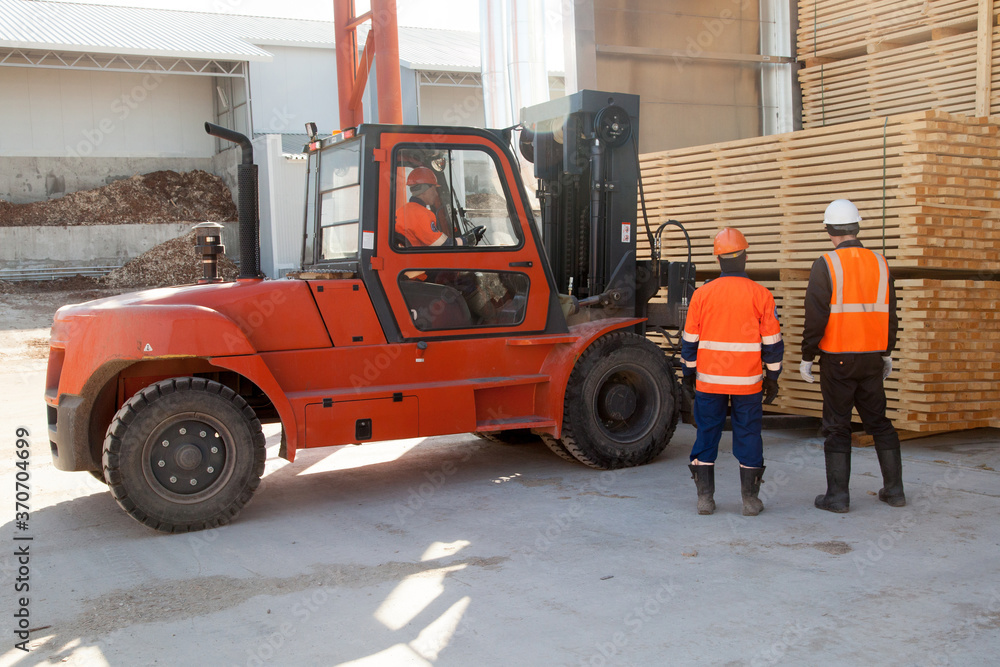 workers load boards with an industrial loader at a sawmill