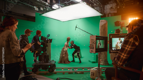 On Big Film Studio Professional Crew Shooting History Costume Drama Movie. On Set: Directing Green Screen Scene with Beautiful Lady Wearing Renaissance Costume Meets Actor Playing Monster photo