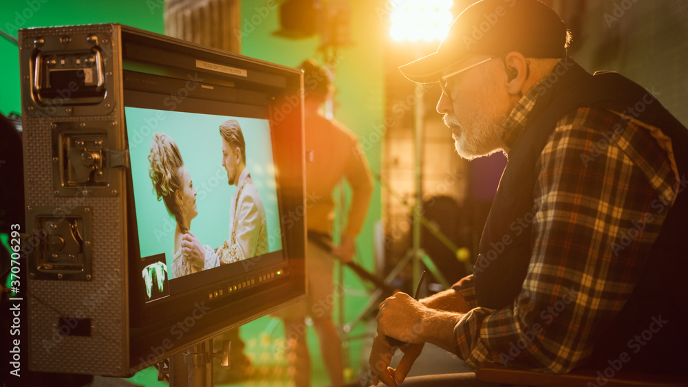Fototapeta premium Director Looks at Display Controls Shooting Period Drama Movie. Green Screen CGI Scene with Actors Wearing Renaissance Costumes. Crew Shooting High Budget Movie. Side View