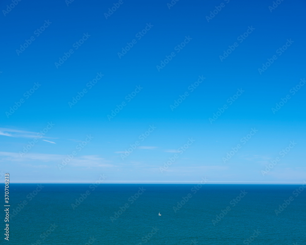 lonely sailing boat on vast blue water area of atlantic ocean