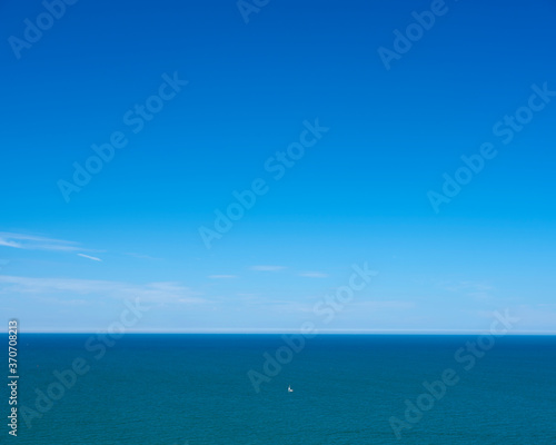 lonely sailing boat on vast blue water area of atlantic ocean