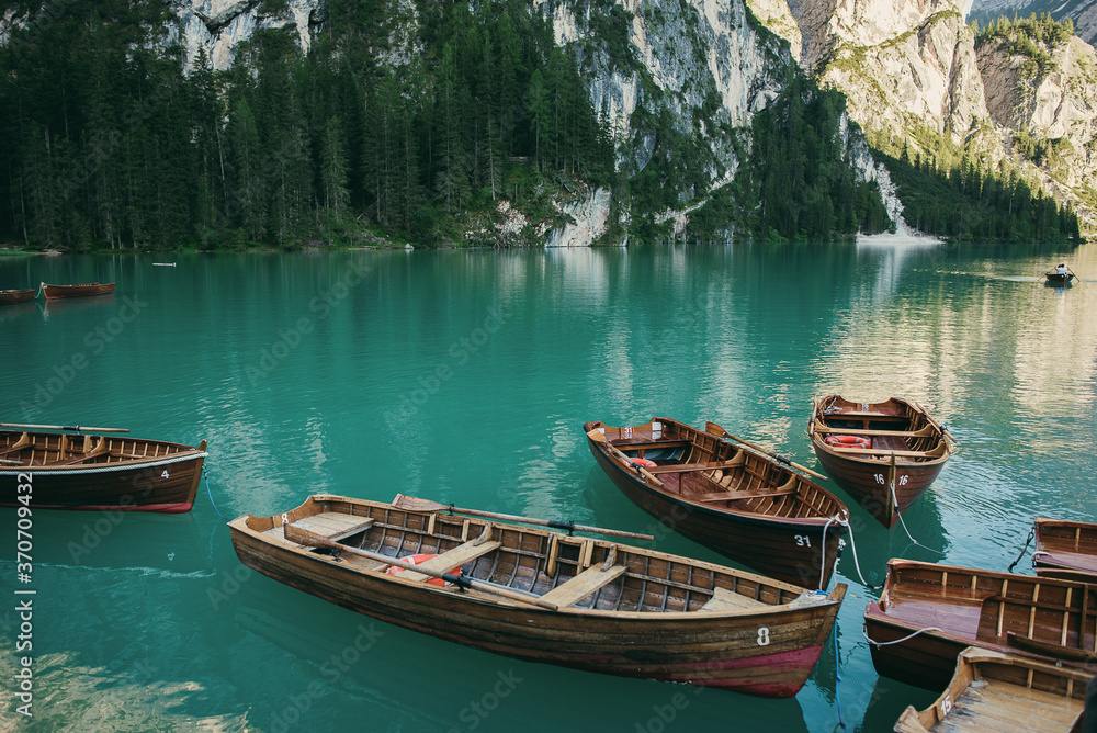Wooden rowing boats parked near a dock in a river or lake. Beautiful mountain landscape and scenery during summer season.