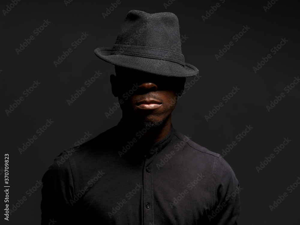 portrait of a young African man in a black hat. Black background studio photography portrait of a young African man in a black hat. Black background studio photography