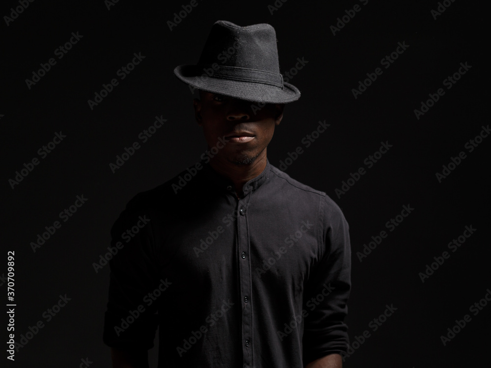 portrait of a young African man in a black hat. Black background studio photography portrait of a young African man in a black hat. Black background studio photography