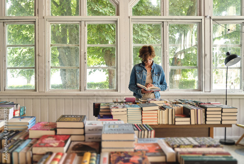 Bilde på lerret Lonely woman customer reading a book in old vintage bookshop