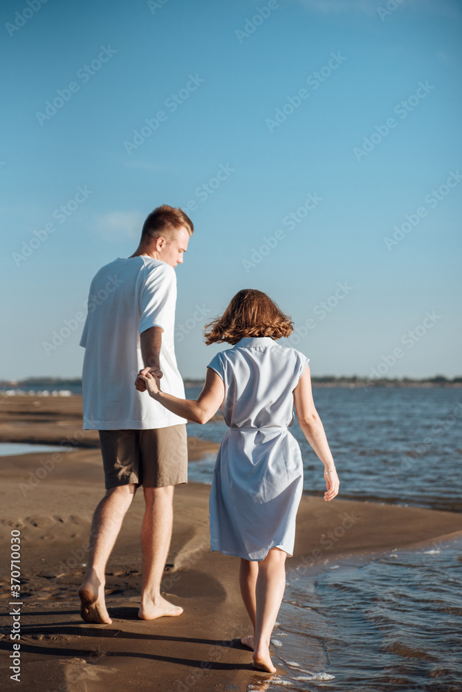 Couple in love on the beach.Young man and woman walking on seashore and laughing. Couple in love on the beach.Young man and woman walking on seashore and laughing.