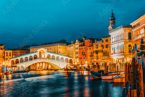 Rialto Bridge (Ponte di Rialto) or Bridge of Sighs and view of the most beautiful canal of Venice - Grand Canal and boats, gondolas, mansions along. Night view. Italy. © BRIAN_KINNEY