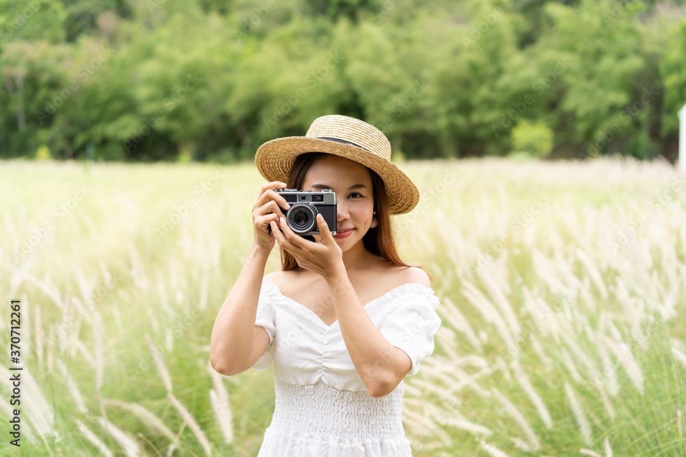 Young asian woman phographing and enjoying in the flower field while traveling in summer