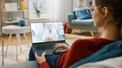 Foto Young Girl Sick at Home Using Laptop Computer to Talk to Her Doctor via Video Conference Medical App