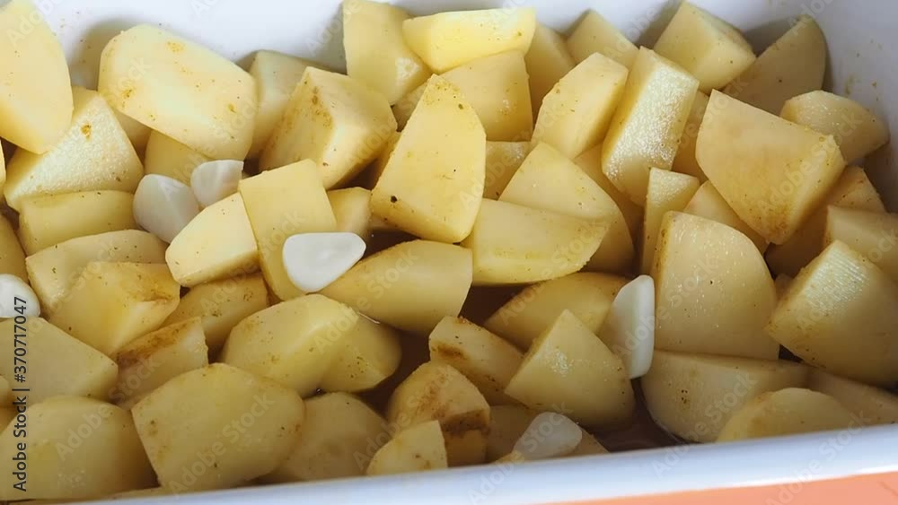 Garlic slices are added to the baking tray with potatoes. Garlic slices are added to the baking tray with potatoes.