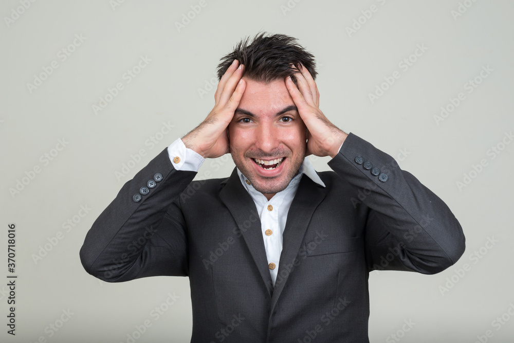 Portrait of happy young handsome Hispanic businessman in suit Portrait of happy young handsome Hispanic businessman in suit