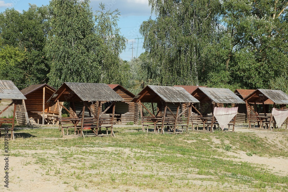 row of empty brown wooden arbors in green grass in front of trees in nature row of empty brown wooden arbors in green grass in front of trees in nature